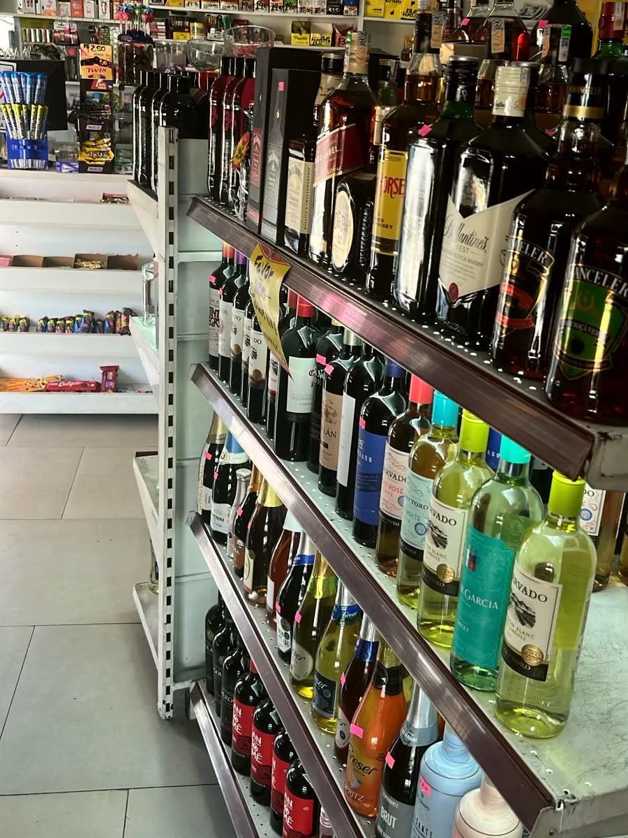 Prateleira de whiskies Red Label, White Horse, Ballantine's e Chanceler, com vinhos embaixo